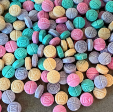 A pile of multicolored counterfeit M30 pills, often referred to as rainbow fentanyl.